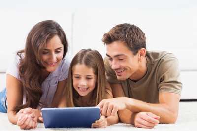 Family lying on a carpet with tablet in the living room